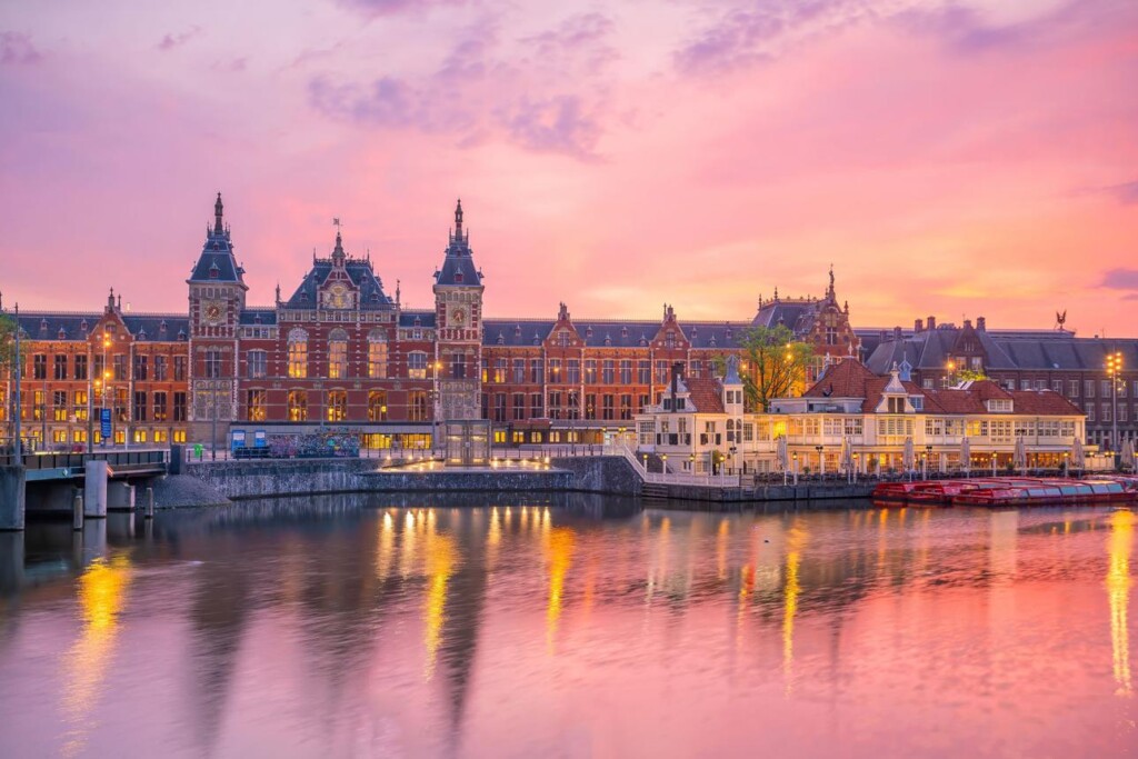 Amsterdam Centraal Station illuminated at sunset beside the canals