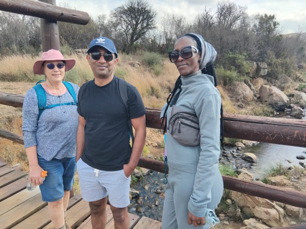Three hikers standing on the wooden bridge above the Klip River during an 11 km Klipriviersberg social hike.