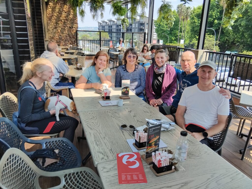 Hikes, Walks & Fitness group members relaxing together over brunch on an outdoor café terrace in Bedfordview.
