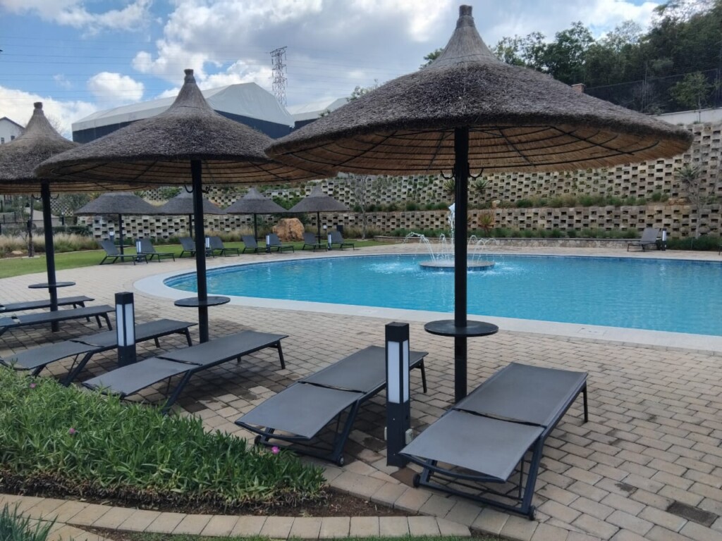 Swimming pool, gardens and thatched umbrellas at Thaba Eco Village